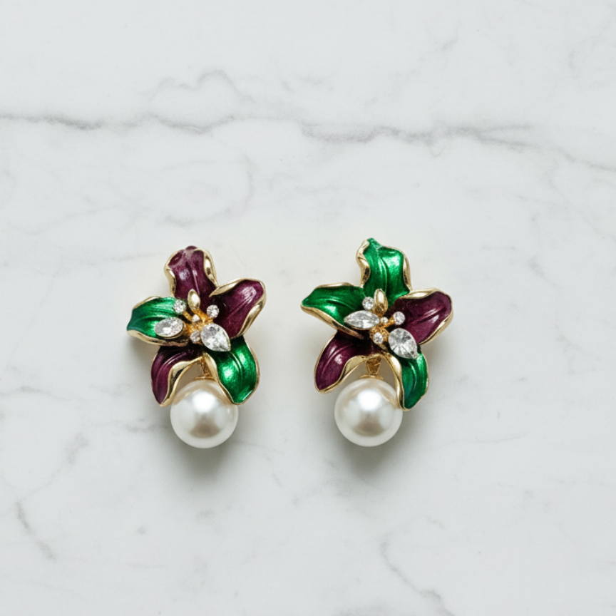 Pair of earrings with floral design and pearls on a marble surface, branded 'Mosa Jewellery'.