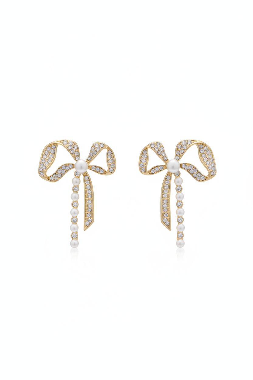 Pair of bow-shaped earrings with pearl details on a black background