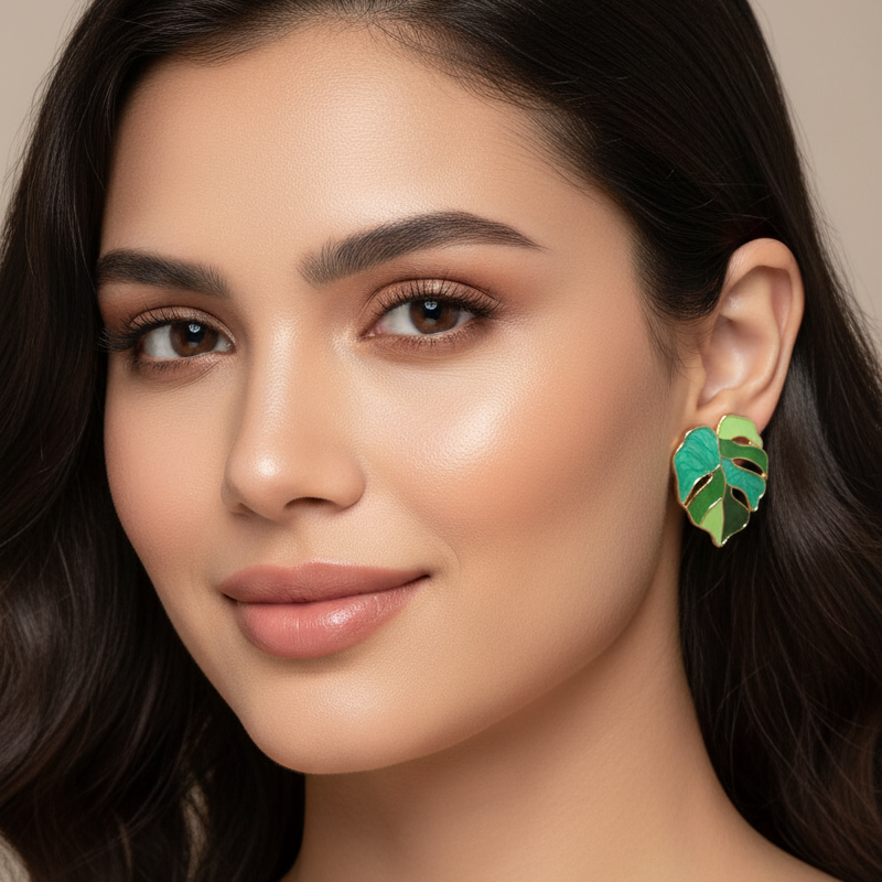 Woman wearing a green leaf-shaped earring against a neutral background