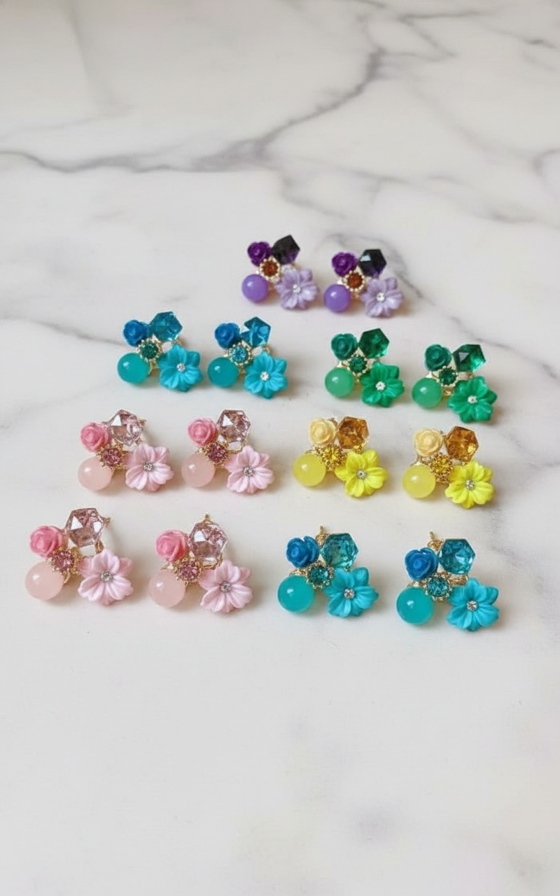 Colorful earrings on geometric podiums against a beige background